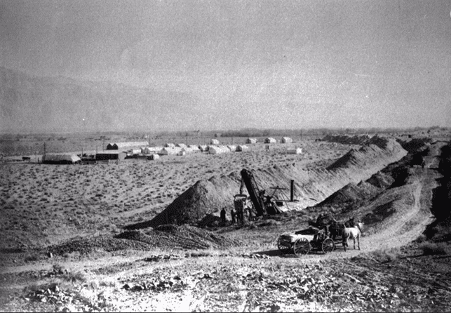 (1912)* - A view of early excavation during the building of the LA Aqueduct to Owens Valley, done between 1907 and 1913. Here we see construction of ditches in the foreground, and the workmen's camp in the background.