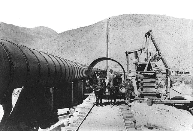 (ca. 1912)* - Photo of a team of mules pulling a section of the aqueduct pipeline on a rail.