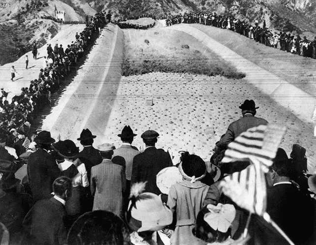 (November 5, 1913)*# - Men, women, and children stand in awe as water is released from the gates at the top of the cascades. Many of the spectators are waiving American flags. Wiliam Mulholland can be seen at right-center of photo just above the American flag.